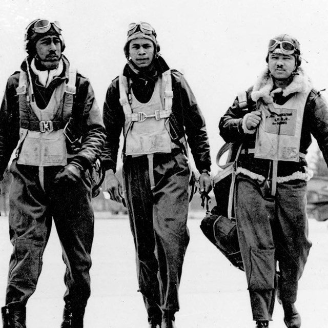 4 African American men in 1940s flight suits walk down runway